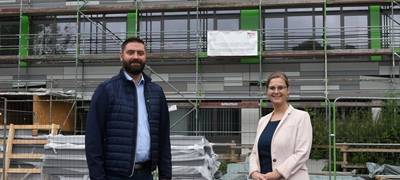 Der Erste Beigeordnete Jens Toschläger und die Beigeordnete Kerstin Heidler vor der neuen Fassade von Haus Nr. 7 der Peter-Weiss-Gesamtschule.