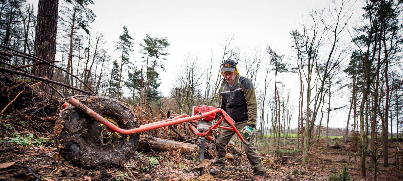 Mit schwerem Gerät werden die Erdbohrer am steilen Hang von den Mitarbeiter*innen bedient. An diesen Stellen werden im Anschluss die neuen Setzlinge gepflanzt.
