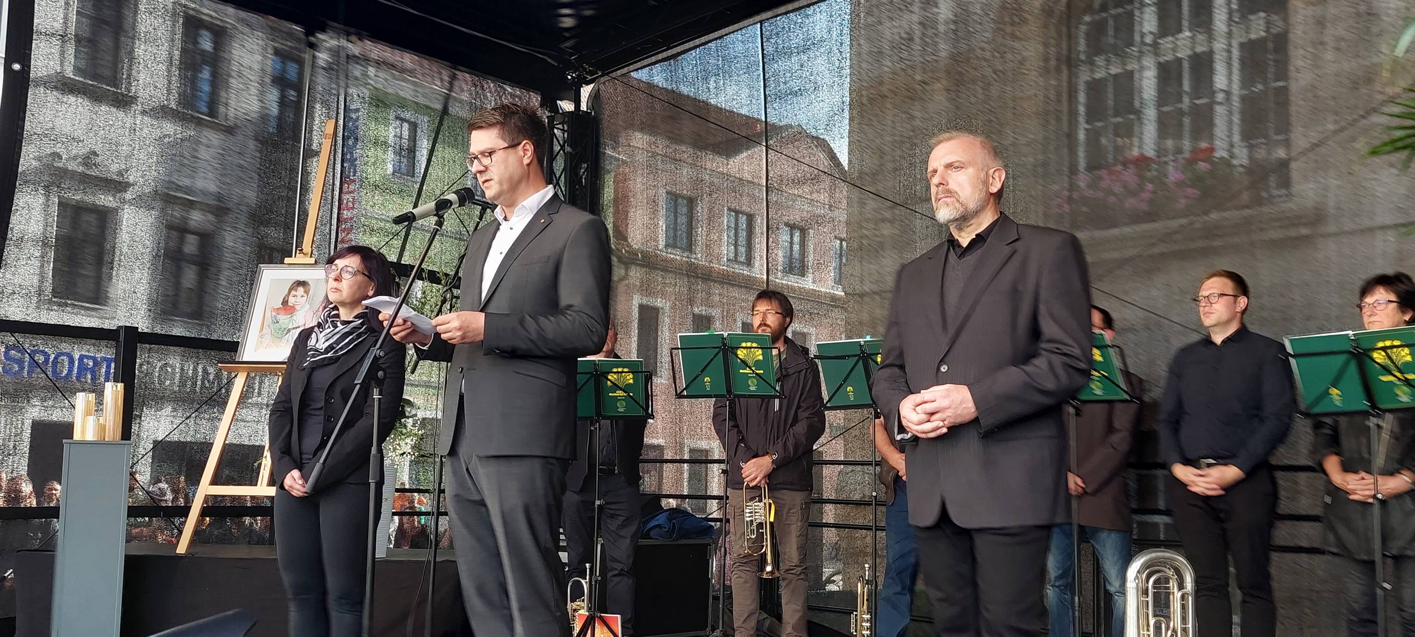 Unnas Bürgermeister Dirk Wigant steht gemeinsam mit Döbelns Oberbürgermeister Sven Liebhauser und dessen Stellvertreterin Susan Zache (von rechts nach links) auf der Bühne bei der Gedenkfeier für die neunjährige Valeriia am 14. Juni 2024 in Döbeln.