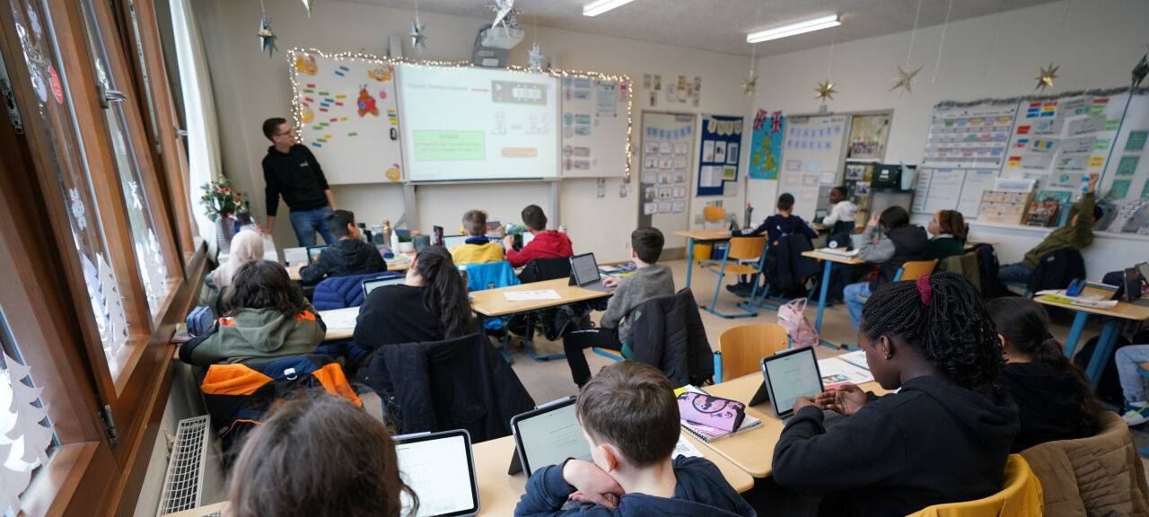 Mathe-Lehrer Tobias Weidenhöffer-Griese (hinten l) leitet den digitalen Mathe-Unterricht in der Klasse 5f in der Lessing-Stadtteilschule in Harburg-Wilstorf