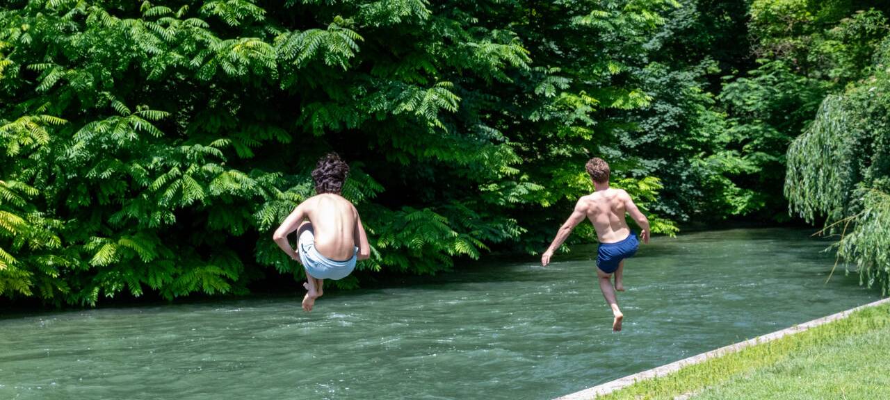 Zwei Jugendliche springen bei heißen Temperaturen zur Abkühlung in einen Fluss.