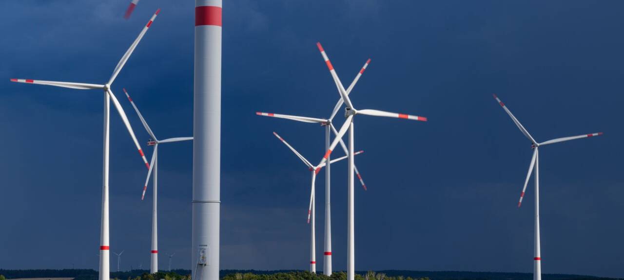 Dunkle Gewitterwolken ziehen über einen Windenergiepark.