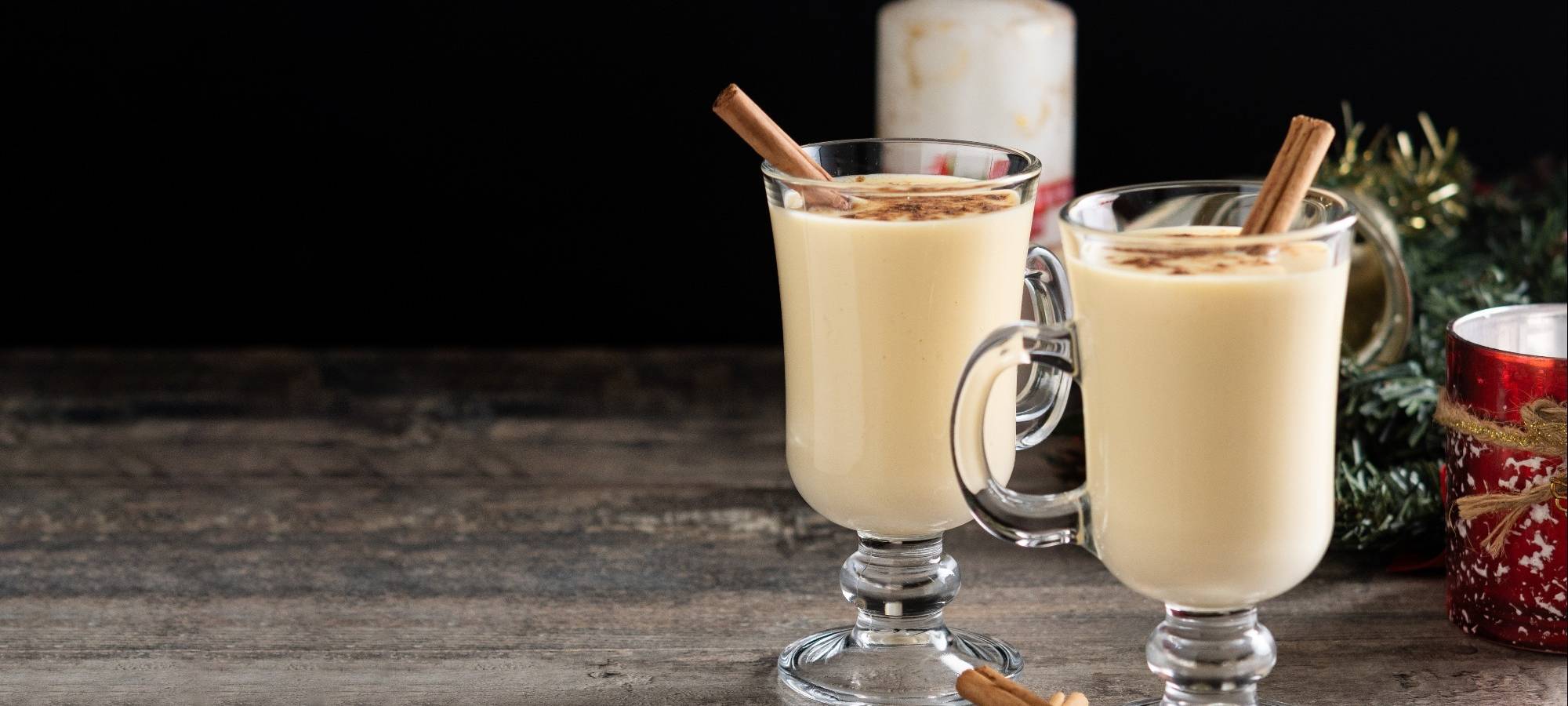 Zwei Gläser mit Eierpunsch stehen auf einem Holzbrett.
