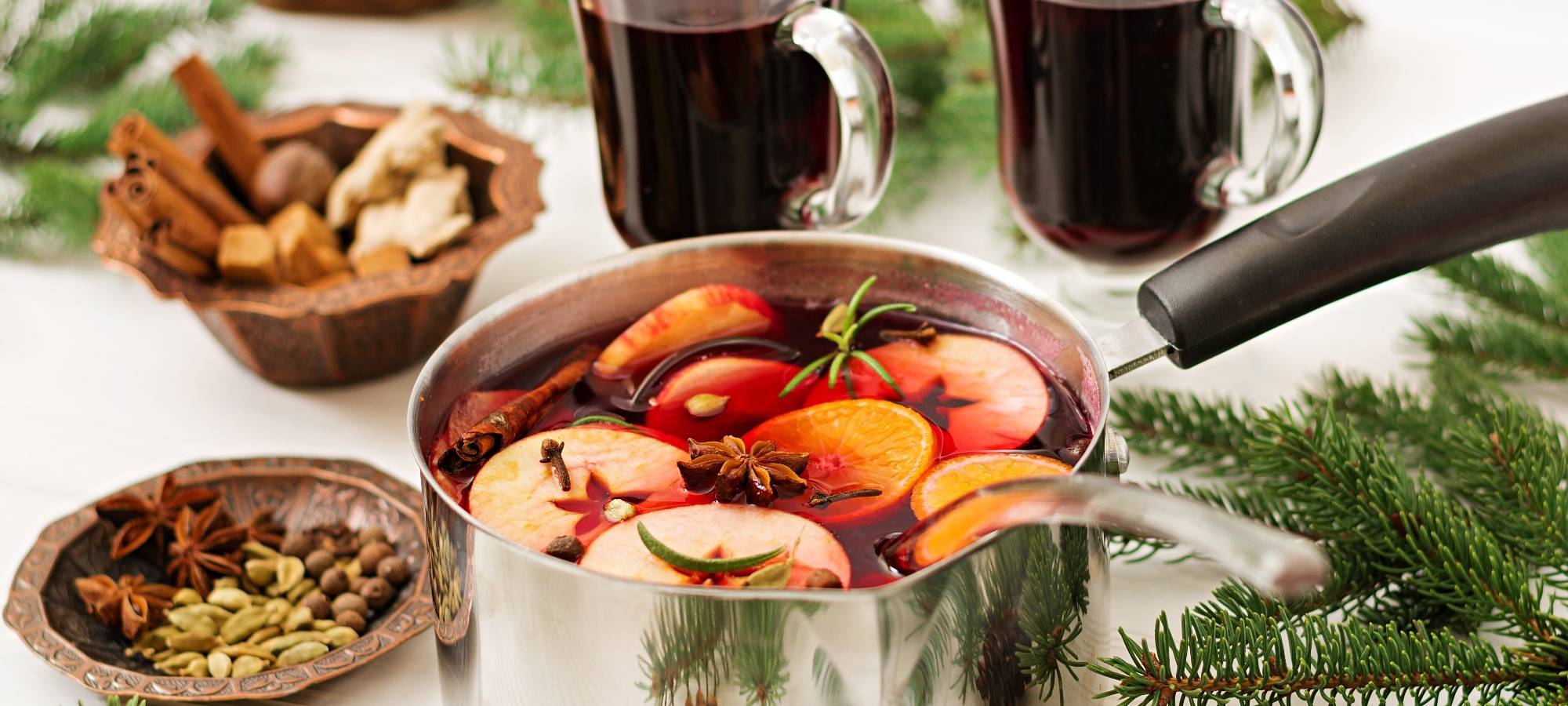 Zwei Gläser mit rotem Glühwein stehen auf einem weihnachtlich geschmückten Tisch.