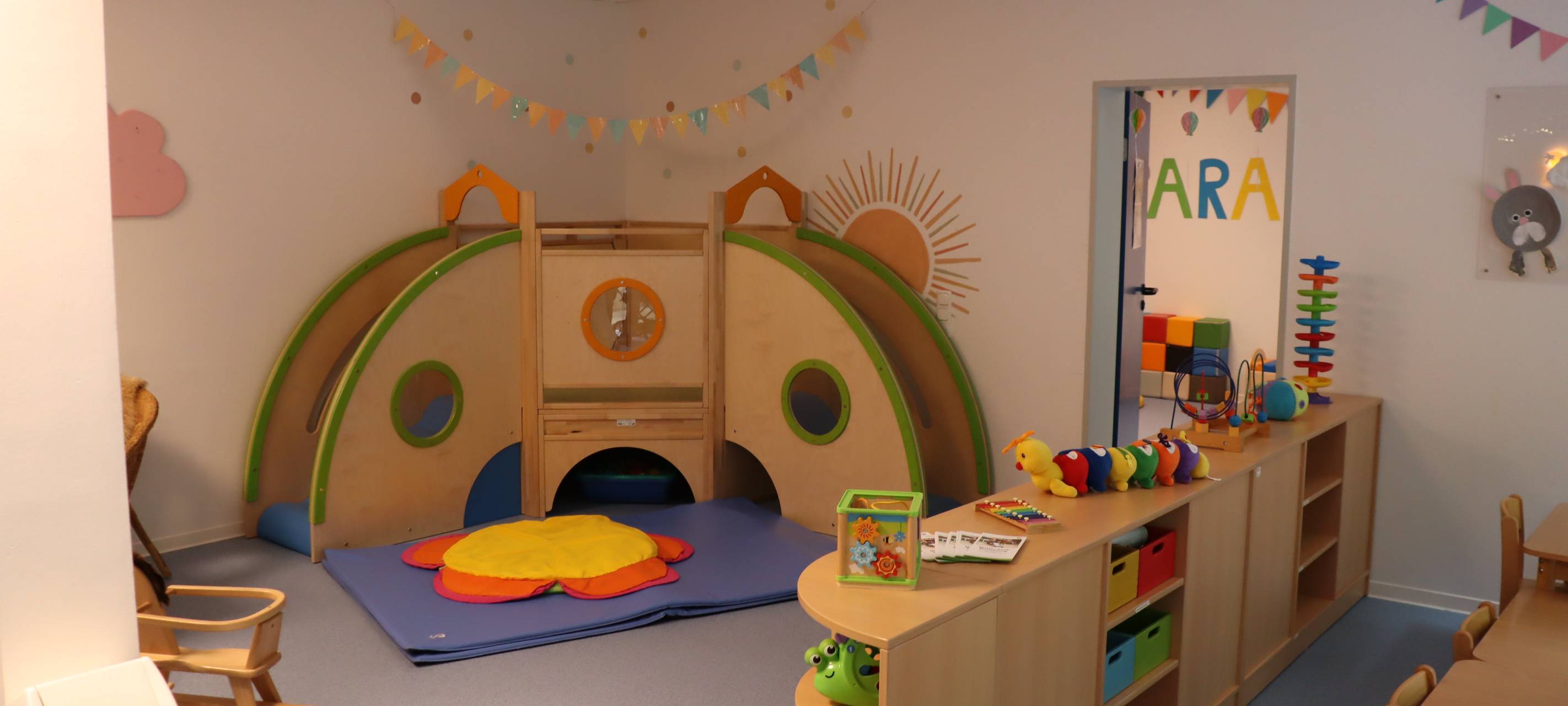 bunter Raum einer Kita mit Holzmöbeln und Spielzeugen