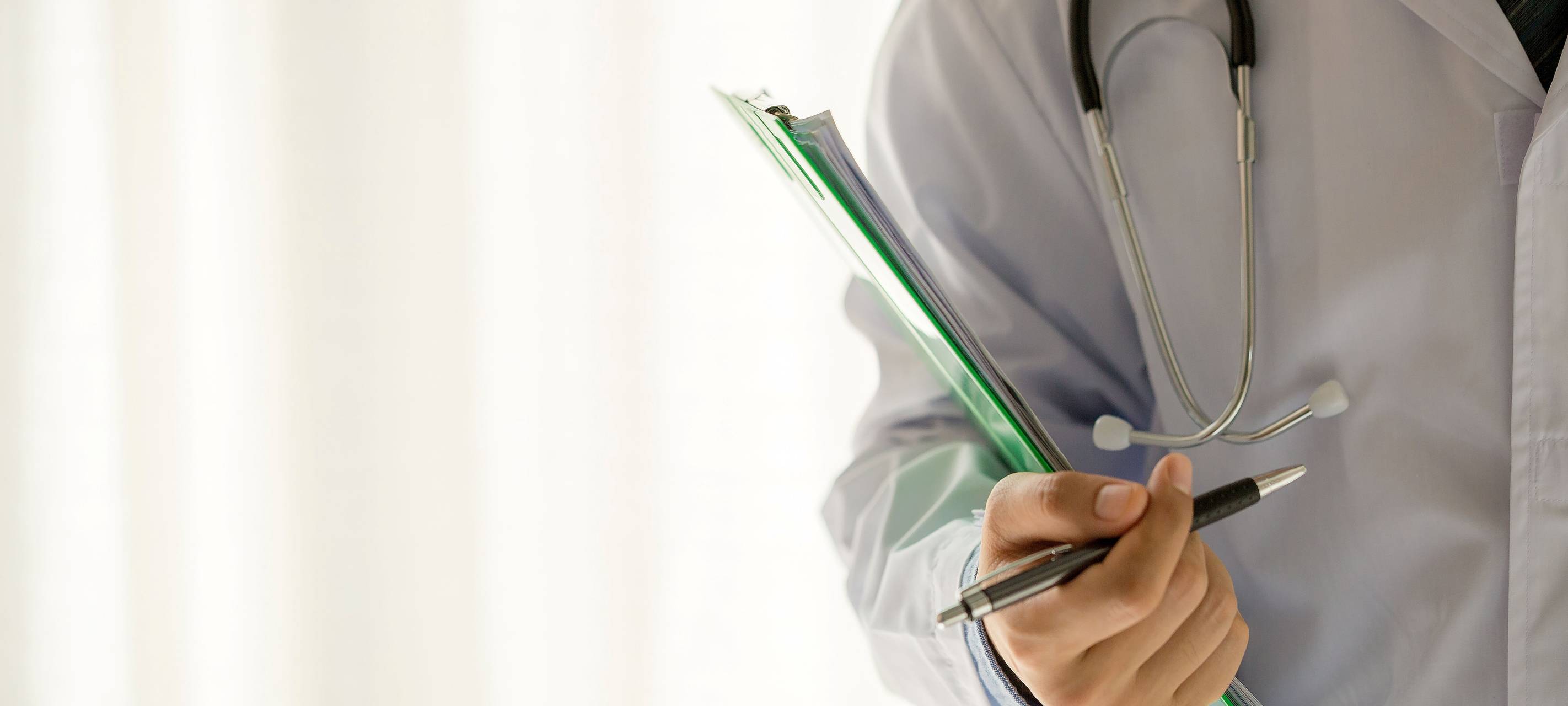 Arzt mit Stethoskop um den Hals und einer Akte in der Hand