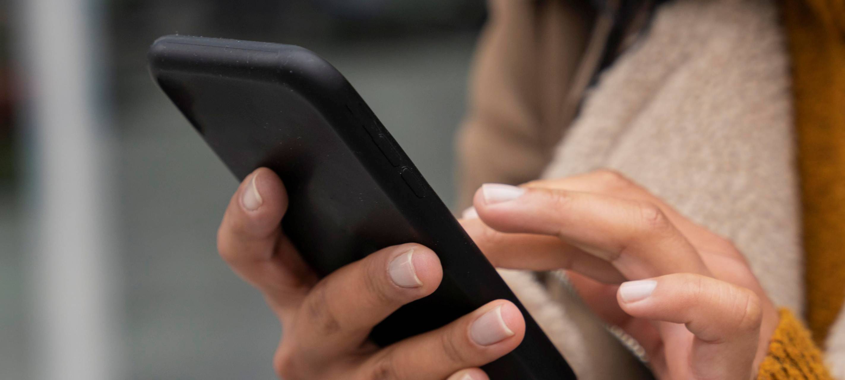 Hände einer Frau die auf ihr Smartphone tippt