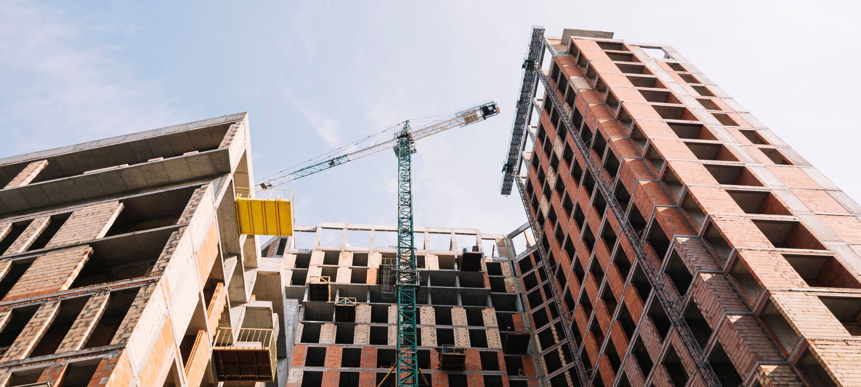 Rohbau eines Gebäudes vor dem ein Kran steht