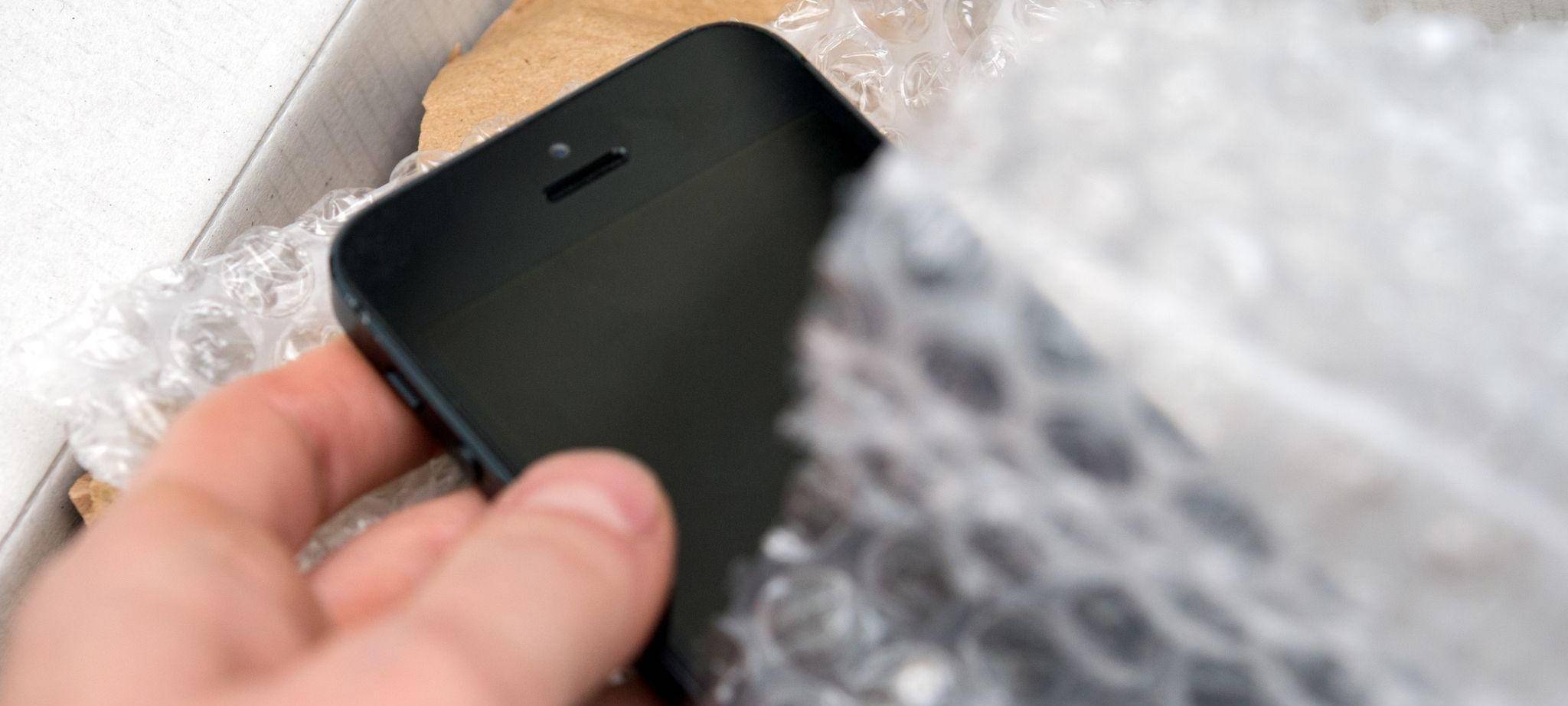 Person nimmt ein Smartphone aus einem Päckchen