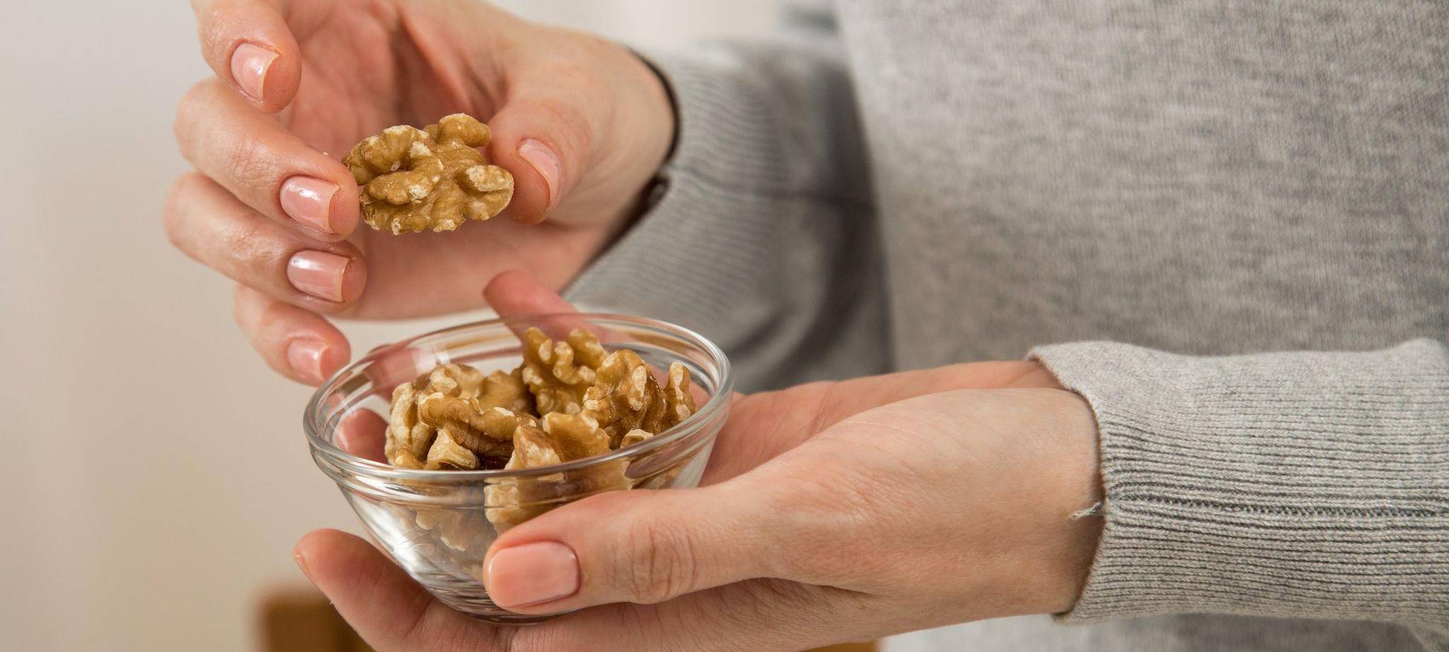 Eine Frau hält ein Schälchen mit Walnüssen in der Hand